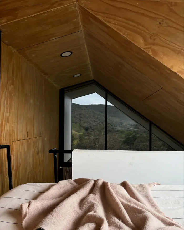 La cama del mezzanine con una manta, bajo el techo de madera