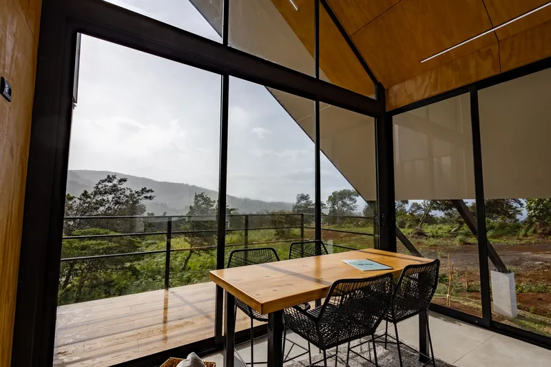 Comedor junto a los ventanales, con la terraza y el valle afuera
